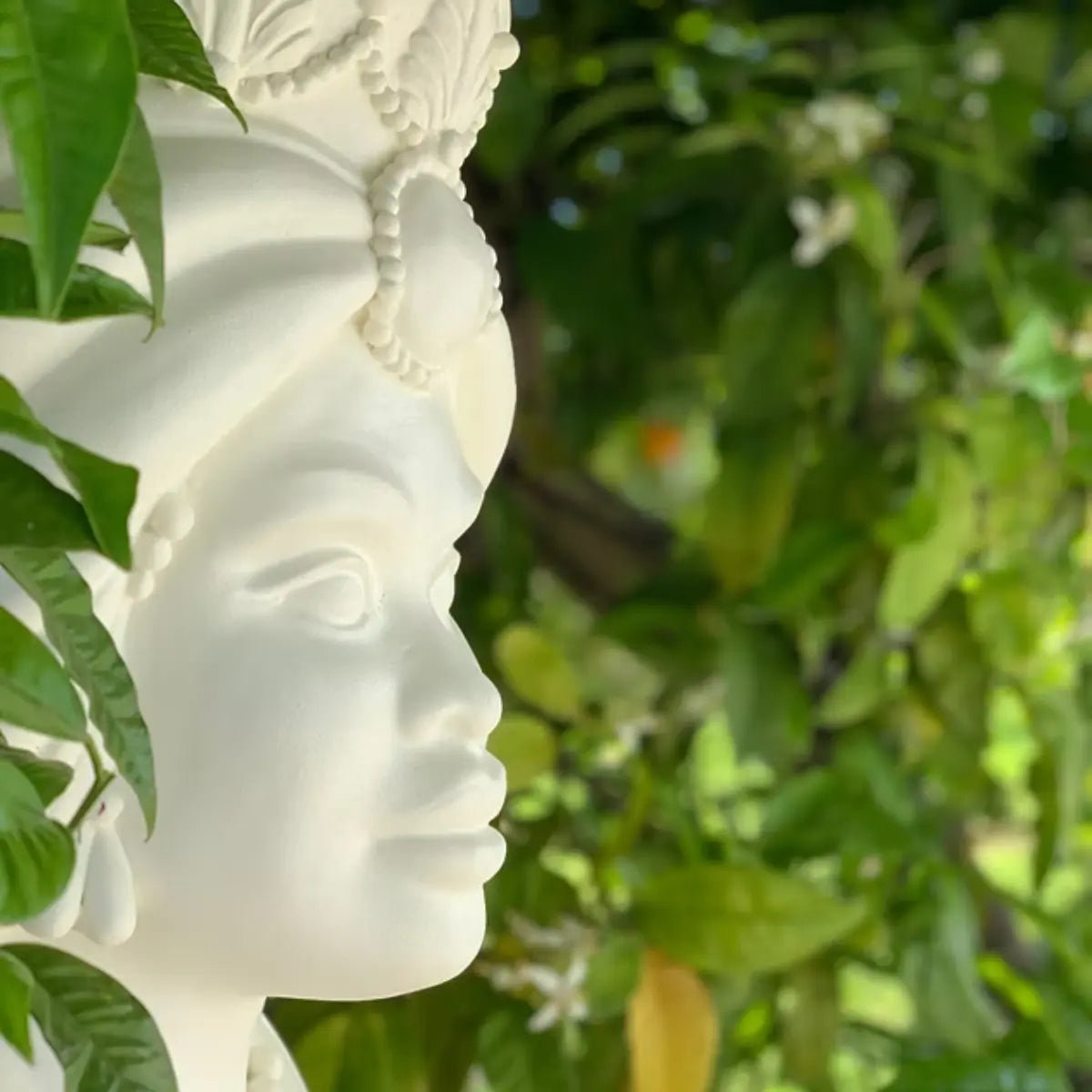 Tavolino testa di moro con figura femminile di colore bianco posizionato tra le siepi