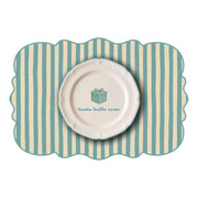 Tovaglietta dalla forma irregolare a righe bianche e azzurre con al centro un disegno di un piatto bianco con la scritta "tante cose belle" e un pacco regalo azzurro disegnato. Sfondo bianco
