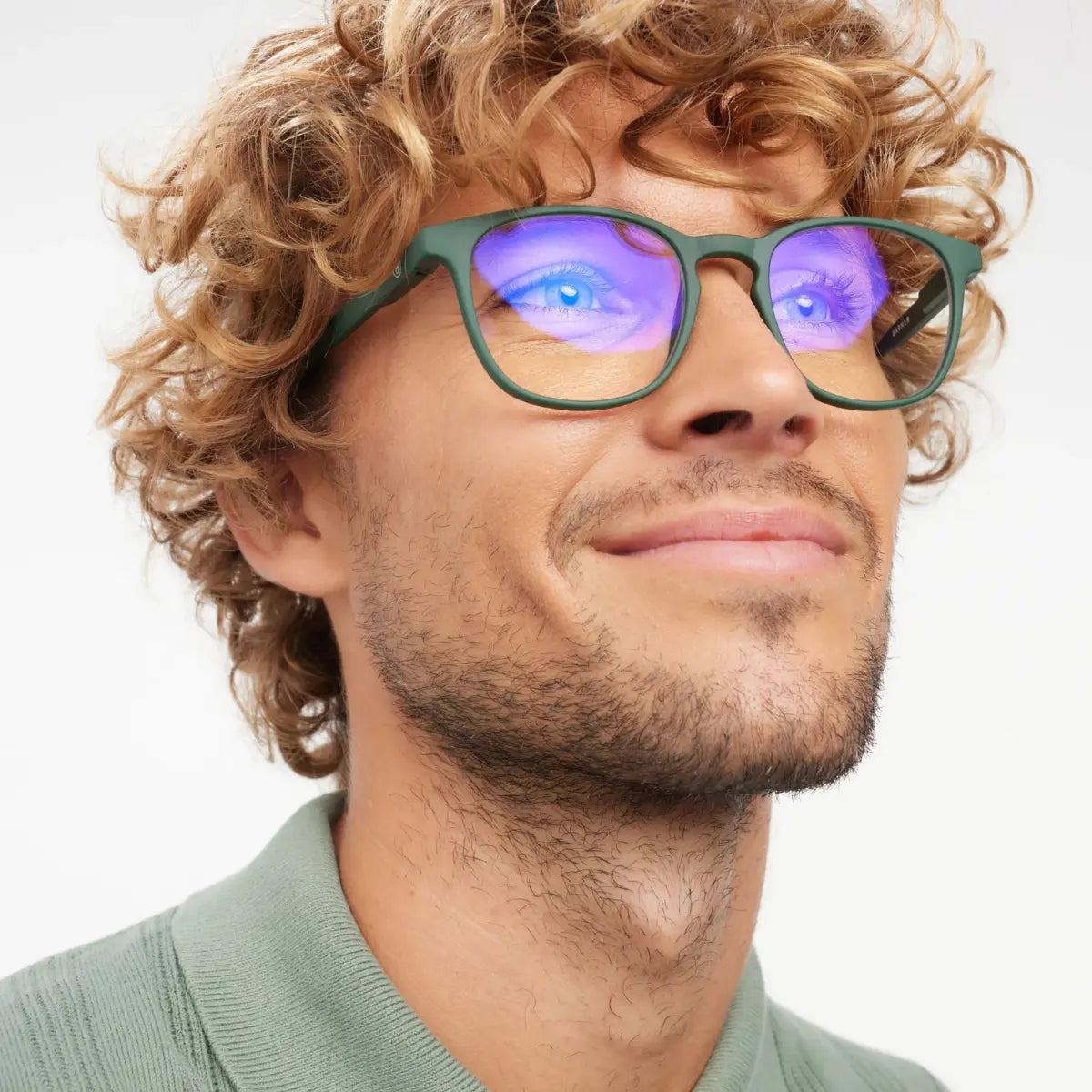 Occhiale con finitura verde opaca, protezione luci blu indossato da uomo riccio biondo