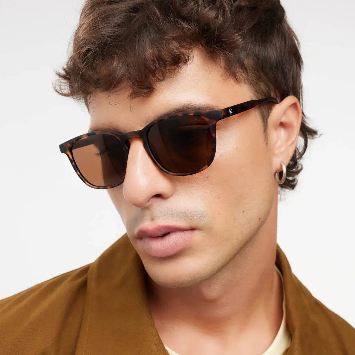 Occhiale da sole marrone design tartaruga finitura opaca, indossato da uomo moro.