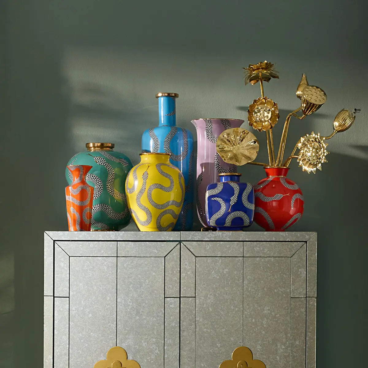 Serie di vasi di diversi colori accomunati dalla fantasia con serpenti a quadretti bianchi e neri