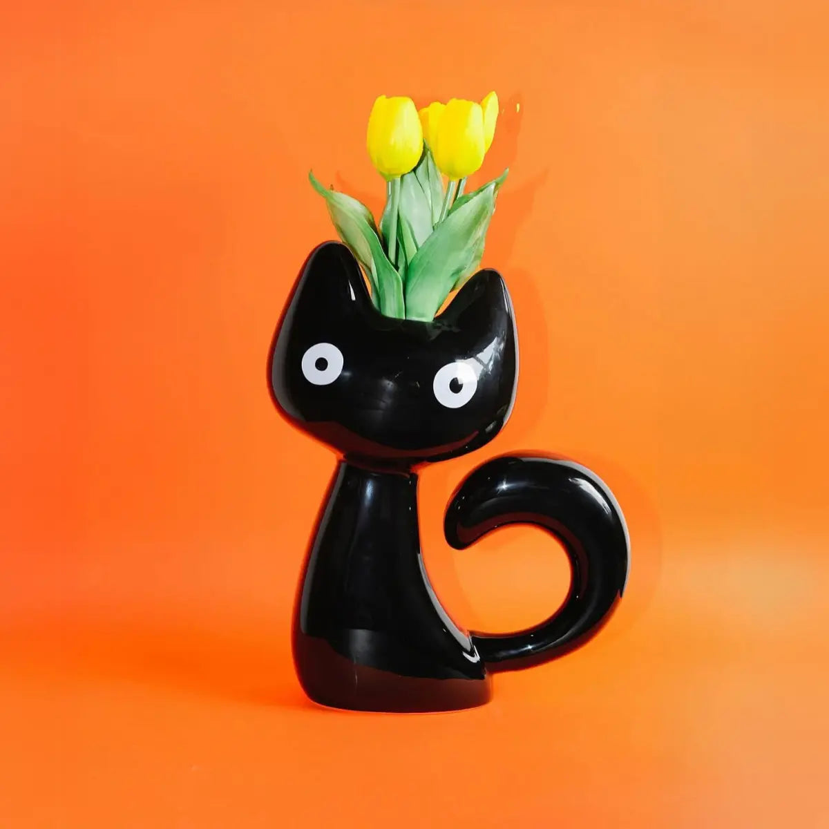 Vaso a forma di gatto nero con tulipani gialli all'interno