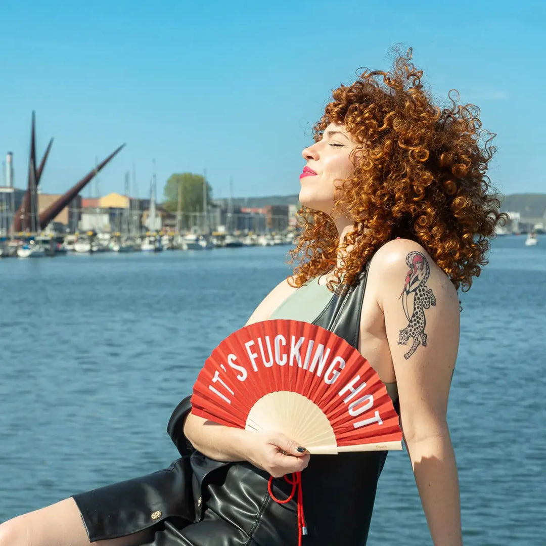 Ragazza con ventaglio rosso con scritta bianca it's fucking hot
