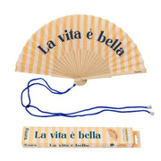 Ventaglio con base a righe gialle e bianche e scritta blu "La vita è bella". Incluso packaging e laccetto per appendere il ventaglio al collo. Sfondo bianco 