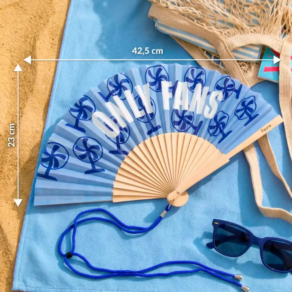 Ventaglio azzurro con disegno di ventilatori blu e scritta bianca "Only fans" appoggiato su un telo mare in spiaggia. Misure con frecce in bianco