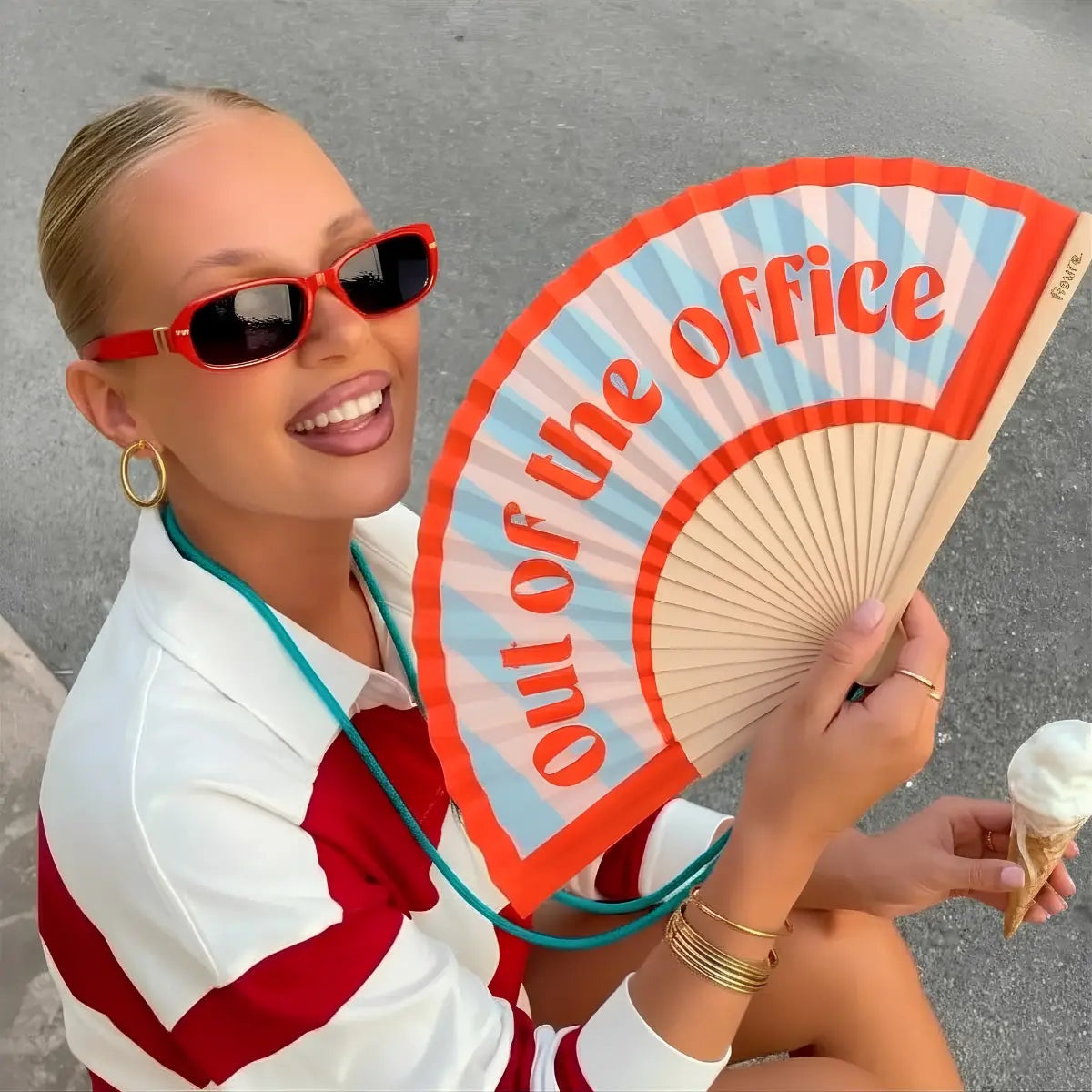 Donna che tiene in mano il ventaglio con righe e scritta rossa "out of the office".