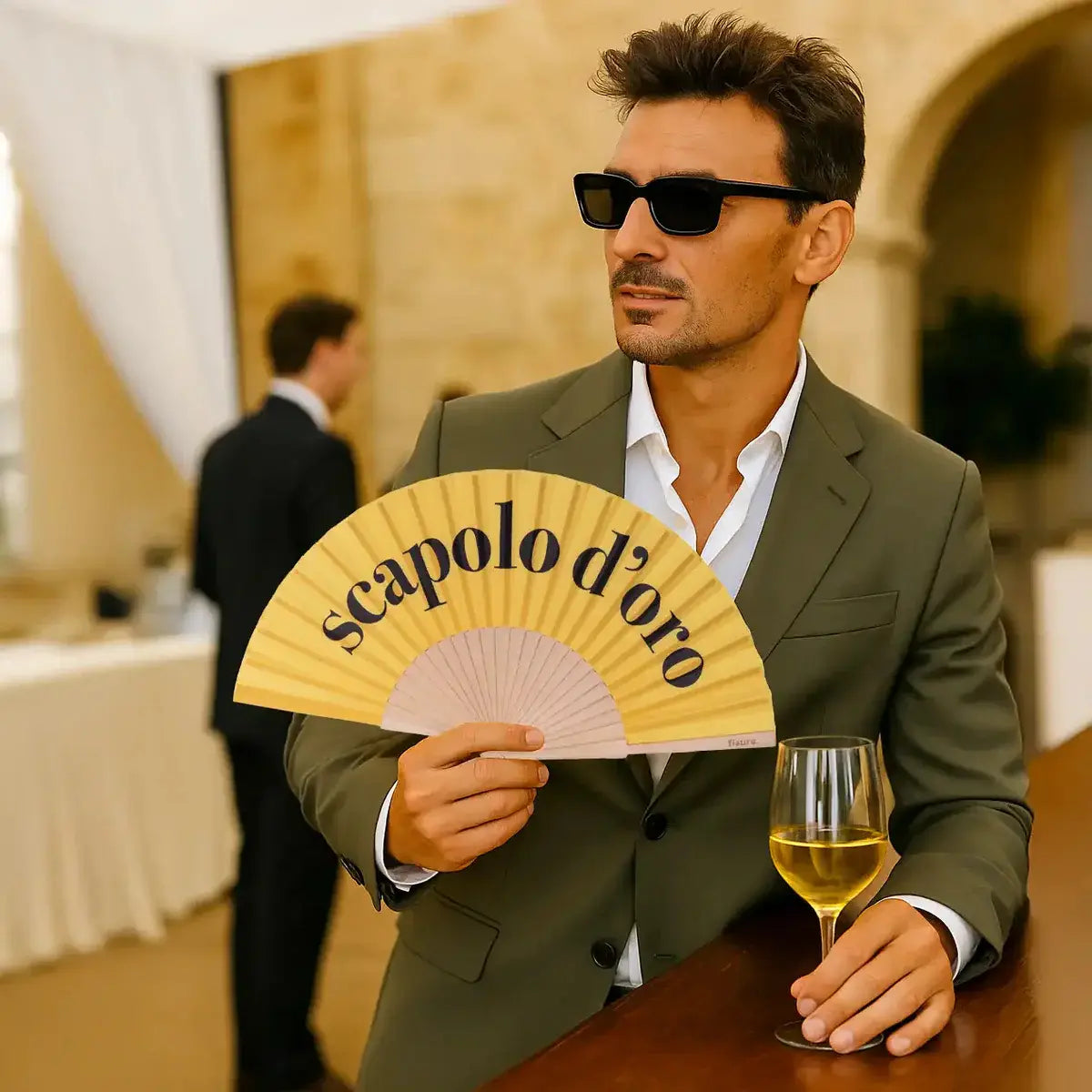 Uomo con ventaglio giallo con scritta nera Scapolo D'oro.