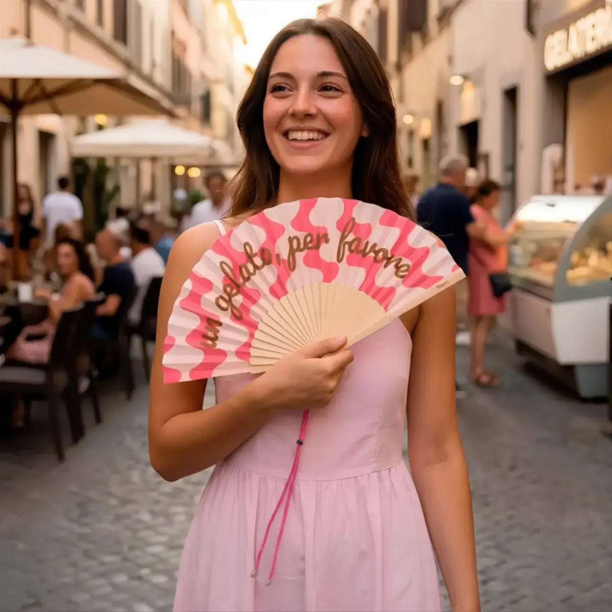 Donna con ventaglio con fantasia rosa e bianca e con scritta "Un gelato per favore"