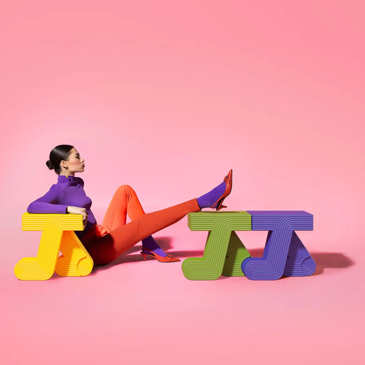 Tavolini colorati con due gambe curve che ricordano un passo in movimento assortiti