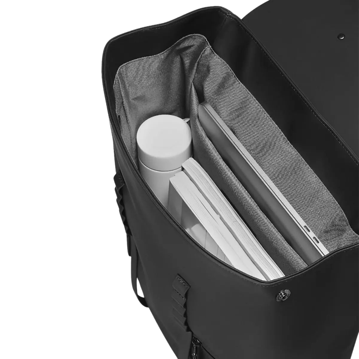 Interno dello zaino con patta nella versione nera. Un computer posizionata nell'apposita tasca, una borraccia bianca e dei libri. Sfondo bianco