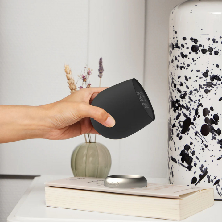 mano che tiene sveglia, vista comodino con libro e vaso 