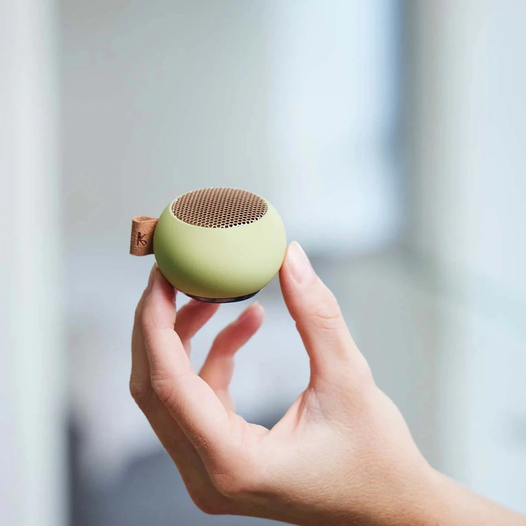 mano che tiene mini cassa audio verde portatile.