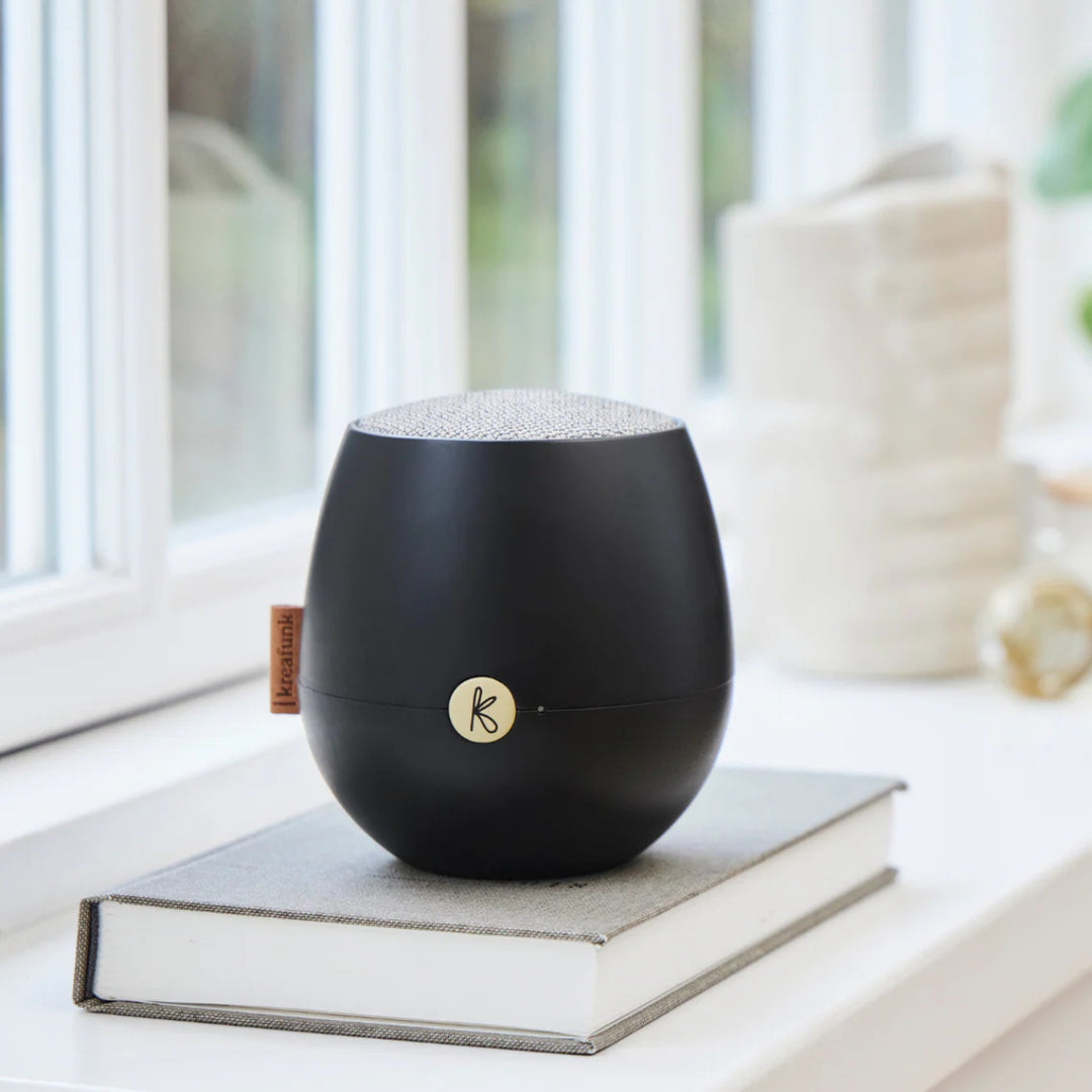 cassa audio portatile nera su libro vicino a finestra