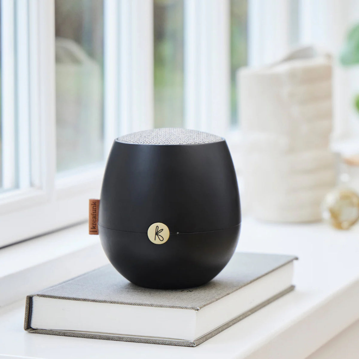 cassa audio portatile nera su libro vicino a finestra