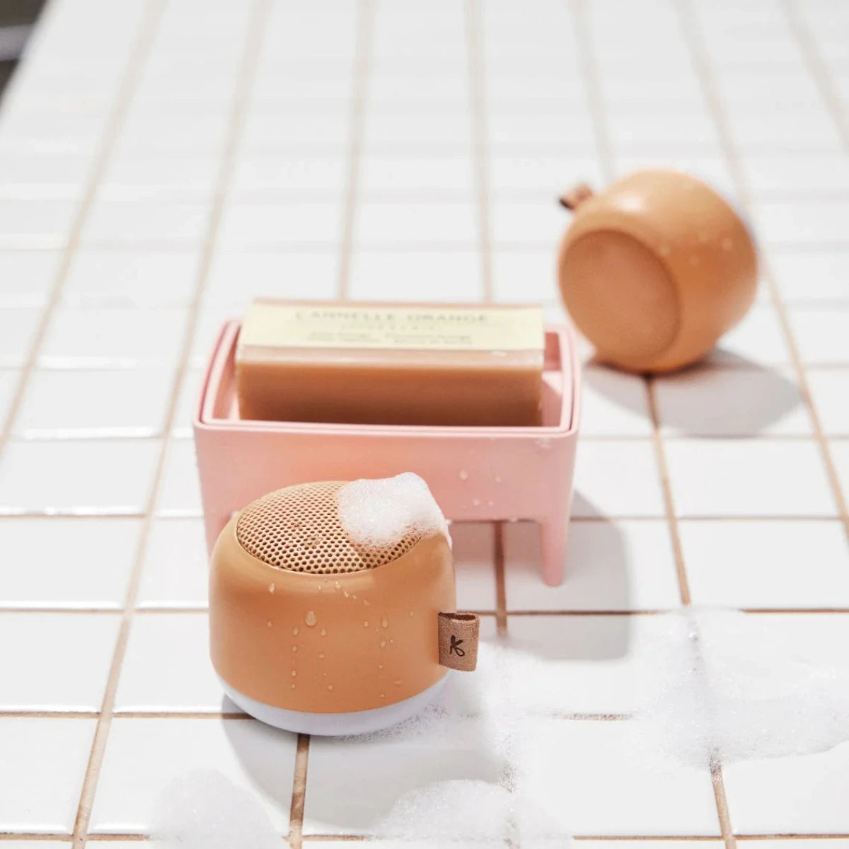 due casse audio portatili arancioni, su piastrelle bianche con schiuma