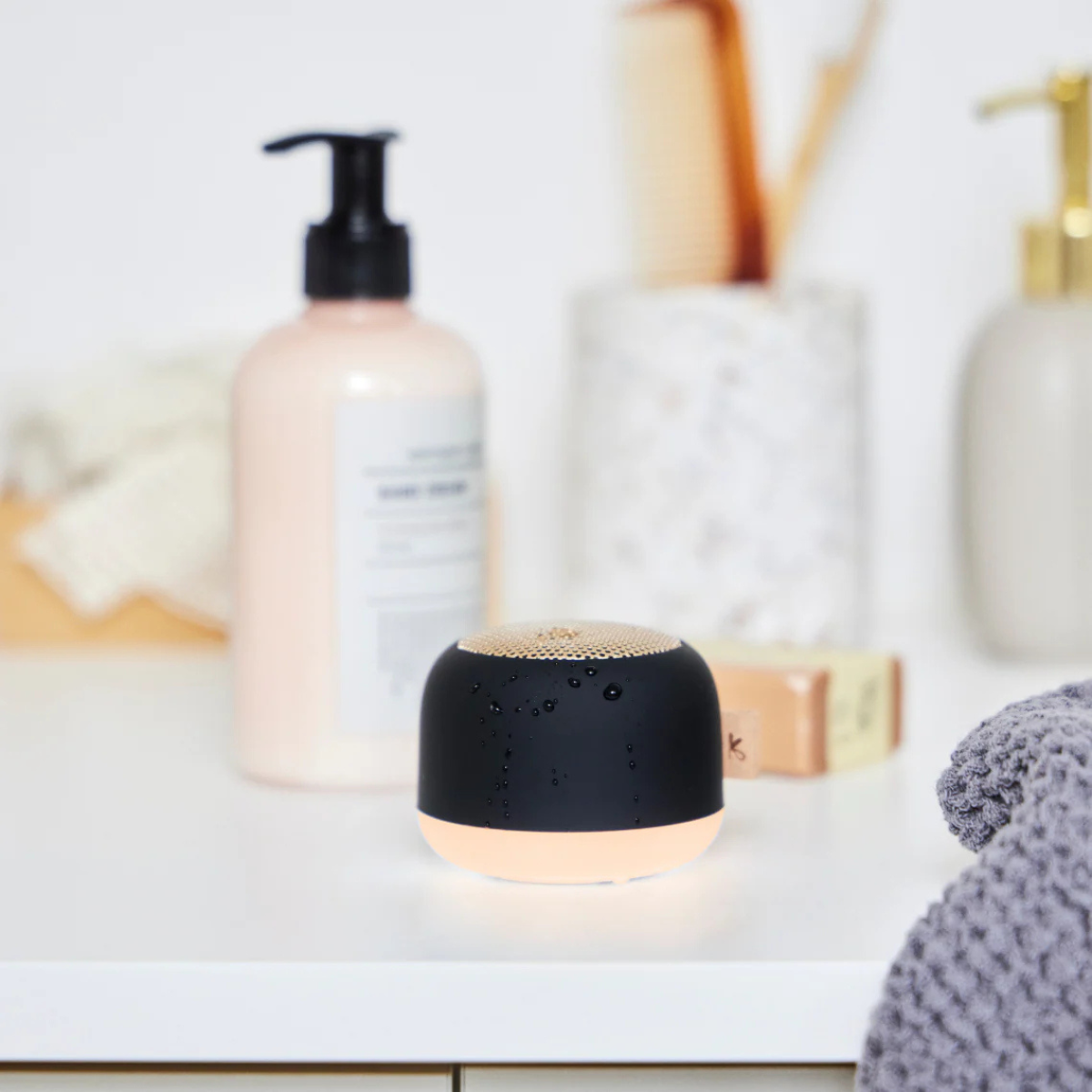 cassa audio portatile nera, su mensola bagno, vicino a sapone