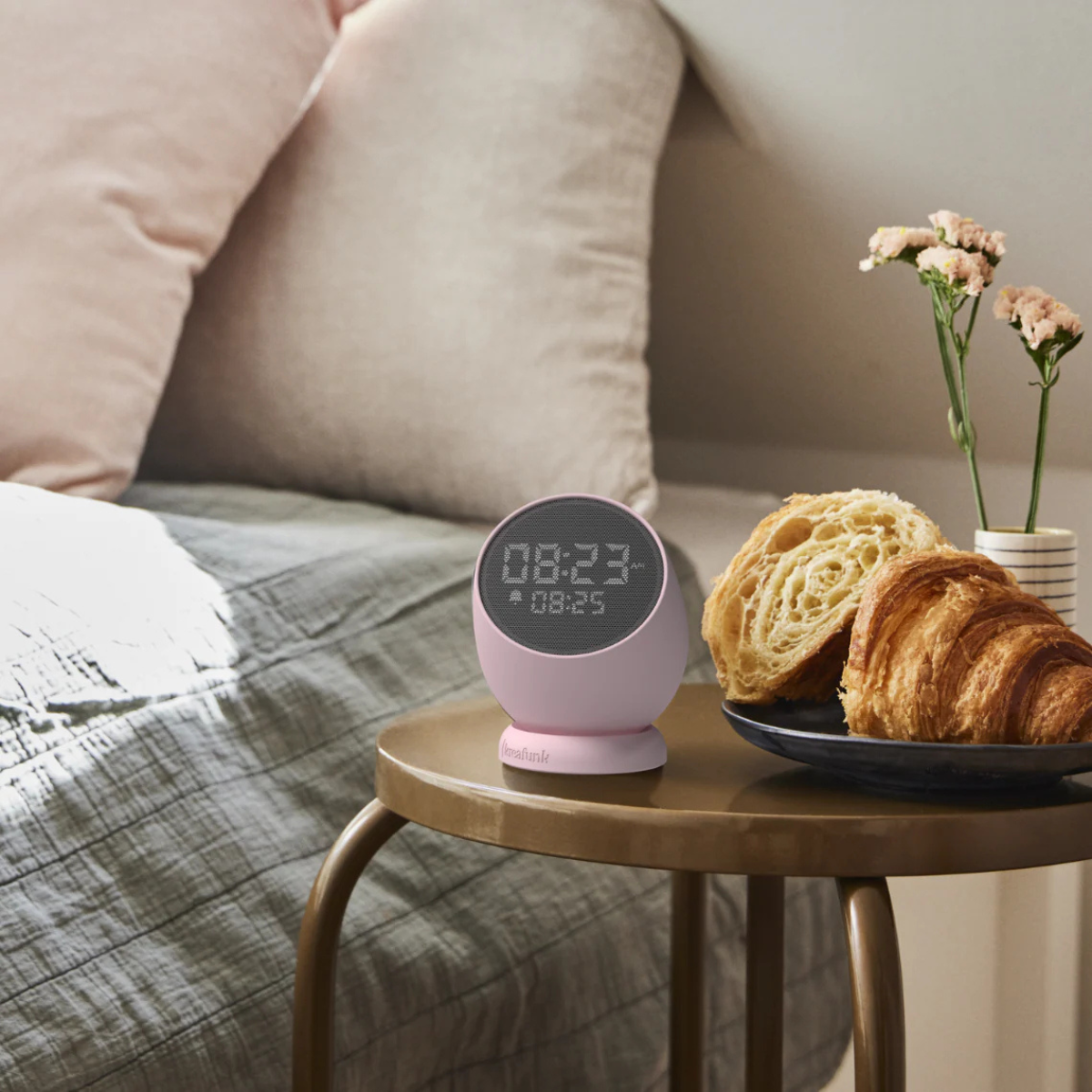 sveglia rosa su tavolino vicino a croissant e fiori