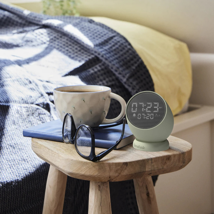 sveglia verde su tavolino, vicino a tazza caffè, occhiali e agenda