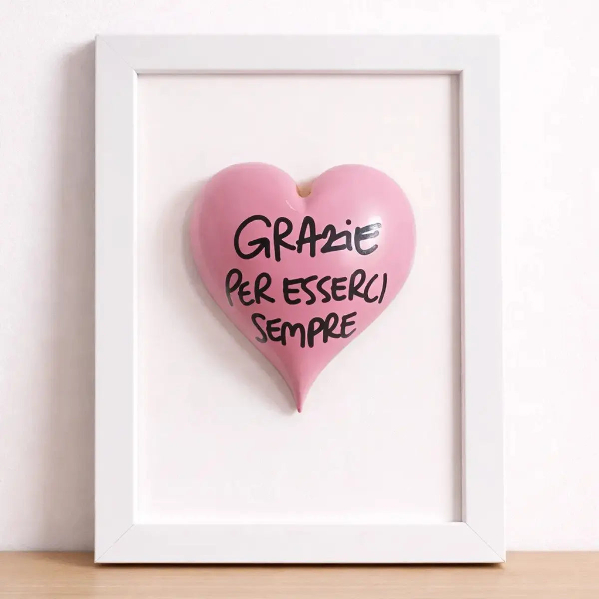 Quadretto CuoreAmore fatto a mano in Italia. Ha una cornice in legno bianca e un cuore in ceramica rosso con una scritta  