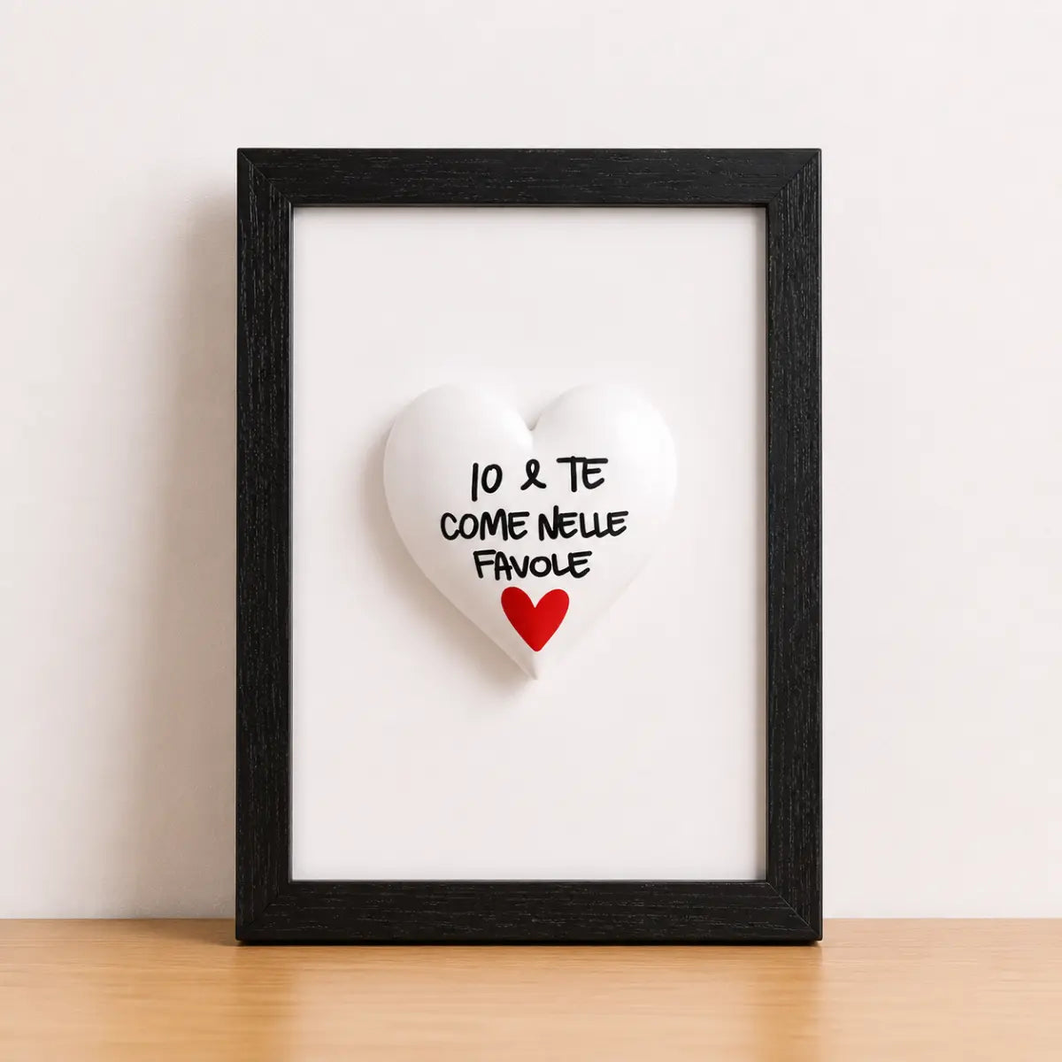Quadretto CuoreAmore fatto a mano in Italia. Ha una cornice in legno nera e un cuore in ceramica bianco con una scritta  